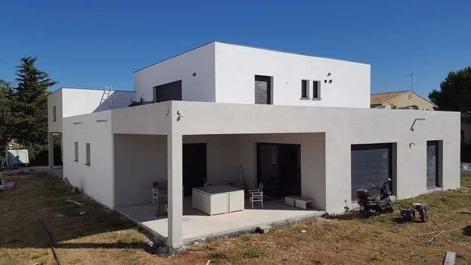 Maison moderne : architecture contemporaine et façade bicolore Architecture moderne à toit plat avec façade bicolore blanche et taupe. Terrasse couverte et jardin en cours d'aménagement sous ciel bleu.